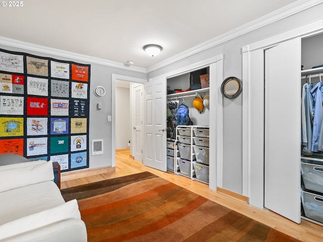 interior space featuring visible vents, wood finished floors, and ornamental molding