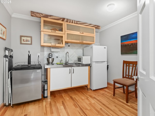 kitchen featuring ornamental molding, white appliances, stainless steel counters, and a sink