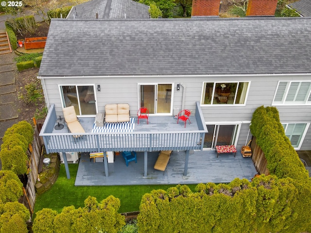 rear view of property with a wooden deck, a yard, roof with shingles, and a chimney