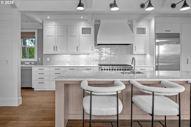 kitchen with white cabinetry, light stone countertops, custom exhaust hood, and stainless steel appliances