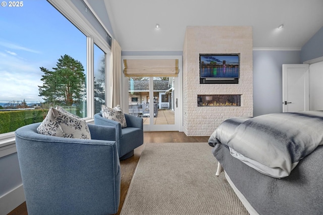 bedroom featuring vaulted ceiling, access to outside, ornamental molding, a fireplace, and hardwood / wood-style floors