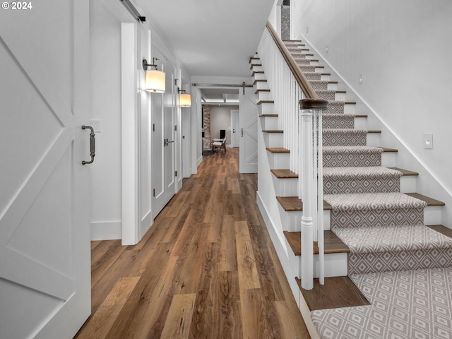 stairway with wood-type flooring and a barn door