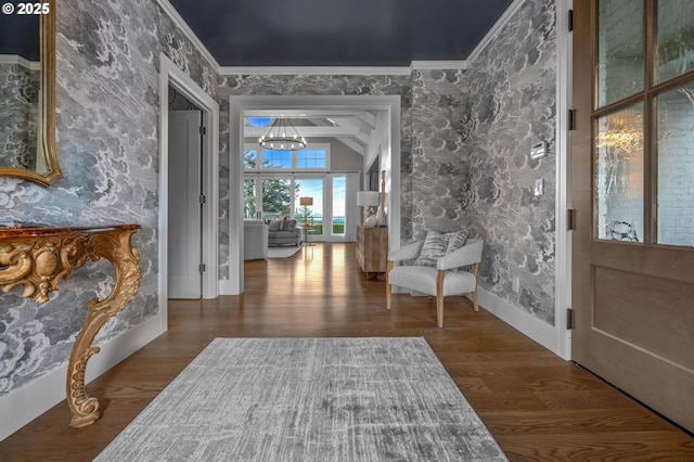 foyer with hardwood / wood-style flooring, ornamental molding, vaulted ceiling, and a chandelier