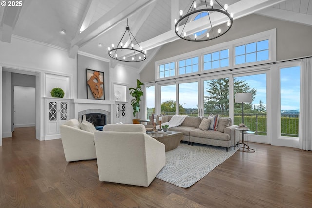 living room featuring a wealth of natural light, beamed ceiling, dark hardwood / wood-style flooring, a notable chandelier, and a premium fireplace