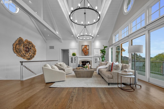 living room featuring beamed ceiling, hardwood / wood-style flooring, a notable chandelier, and high vaulted ceiling