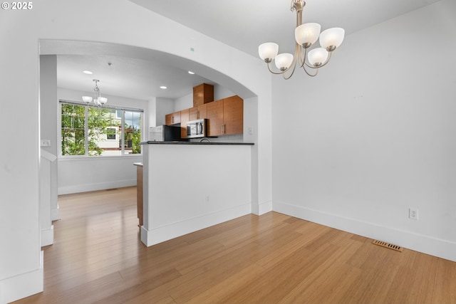 736 NW 118th Ave Unit 102, Portland, OR 97229 - kitchen featuring a chandelier, dark countertops, stainless steel microwave, light wood-type flooring, and recessed lighting