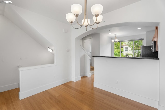 736 NW 118th Ave Unit 102, Portland, OR 97229 - unfurnished dining area featuring a chandelier, arched walkways, and light wood-type flooring