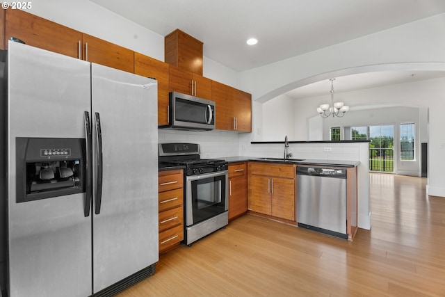 736 NW 118th Ave Unit 102, Portland, OR 97229 - kitchen with stainless steel appliances, dark countertops, a chandelier, a sink, and arched walkways