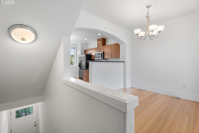 736 NW 118th Ave Unit 102, Portland, OR 97229 - stairway featuring a chandelier, wood finished floors, baseboards, and arched walkways
