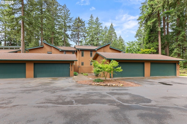 mid-century home with a shingled roof and fence