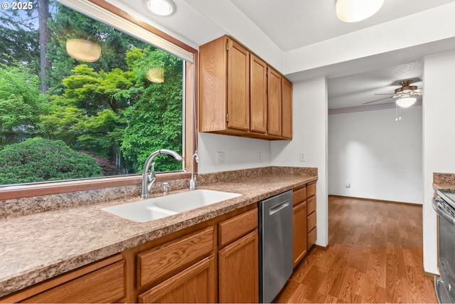 kitchen featuring stainless steel appliances, a sink, wood finished floors, ceiling fan, and brown cabinetry