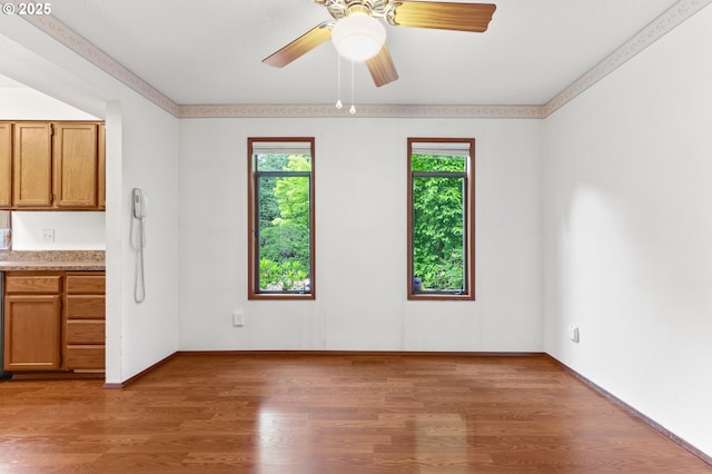 unfurnished room featuring light wood-type flooring, baseboards, and a ceiling fan