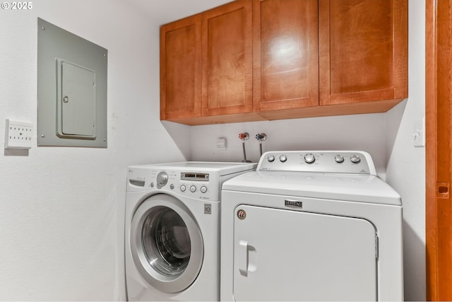 washroom with washing machine and clothes dryer, cabinet space, and electric panel