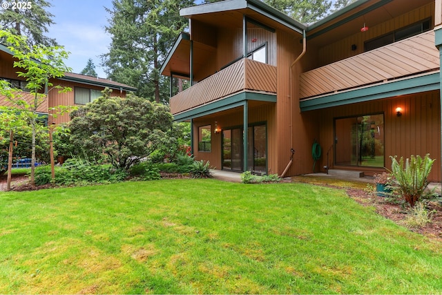 back of house with a balcony and a yard