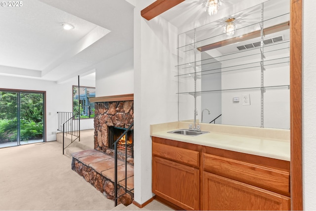 indoor wet bar with light colored carpet, a fireplace, and a tray ceiling