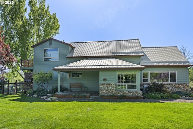 back of property featuring a yard, metal roof, and stone siding