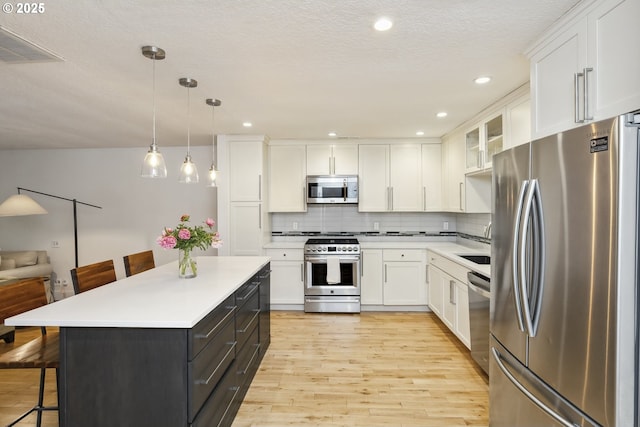 25 SW 143rd Ave, Beaverton, OR 97006 - kitchen with appliances with stainless steel finishes, a breakfast bar area, white cabinets, light wood-type flooring, and recessed lighting
