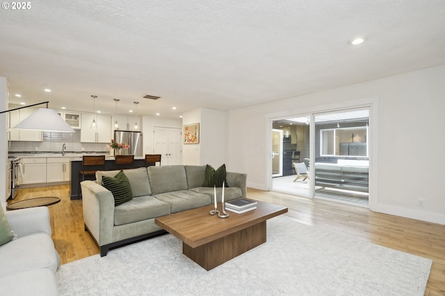 25 SW 143rd Ave, Beaverton, OR 97006 - living area with light wood-type flooring, baseboards, recessed lighting, and a textured ceiling
