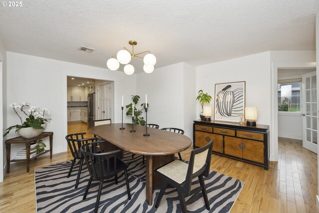 25 SW 143rd Ave, Beaverton, OR 97006 - dining room with light wood-style flooring, a textured ceiling, baseboards, and a chandelier