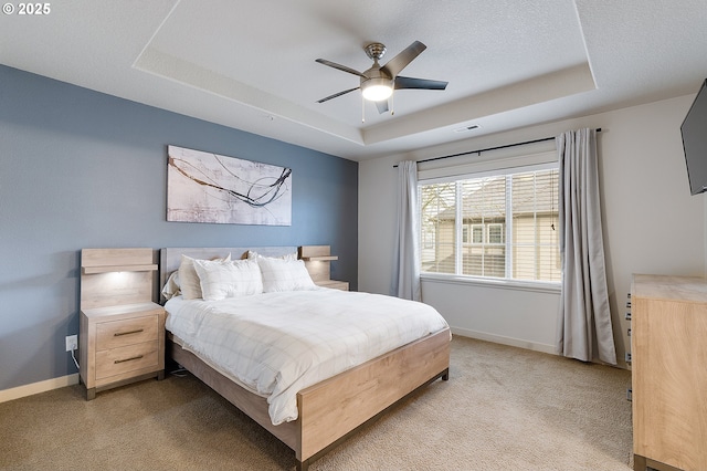 bedroom featuring baseboards, visible vents, a textured ceiling, a raised ceiling, and light colored carpet