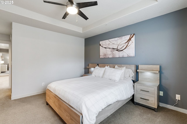 bedroom featuring baseboards, carpet floors, a raised ceiling, and a ceiling fan