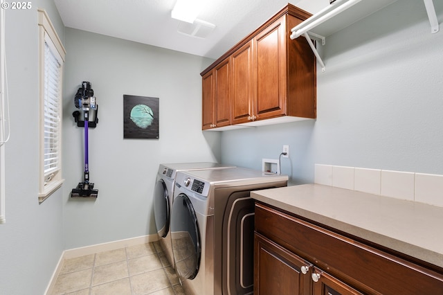 laundry area with light tile patterned flooring, cabinet space, washer and dryer, and baseboards