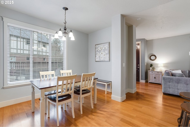 dining room featuring a chandelier, baseboards, and light wood-style floors