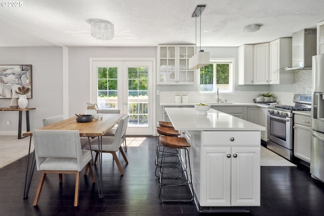 2136 SE Kelly Ave, Gresham, OR 97080 - kitchen featuring gas stove, wall chimney range hood, a kitchen island, light countertops, and a breakfast bar area