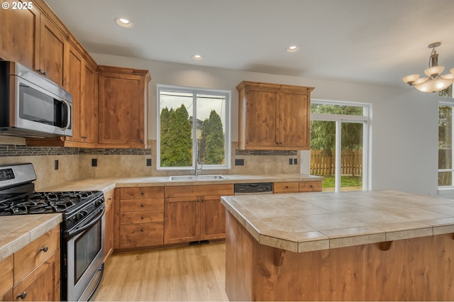 kitchen with a wealth of natural light, a sink, appliances with stainless steel finishes, and tile counters