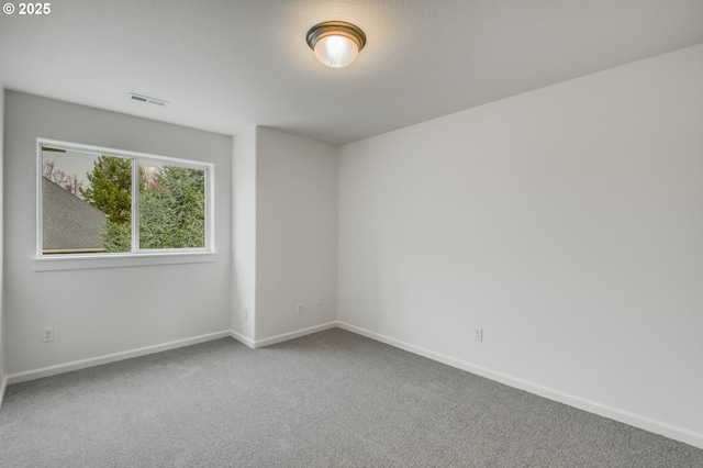 empty room featuring visible vents, baseboards, and carpet