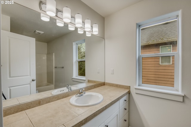 bathroom with visible vents, a washtub, and vanity