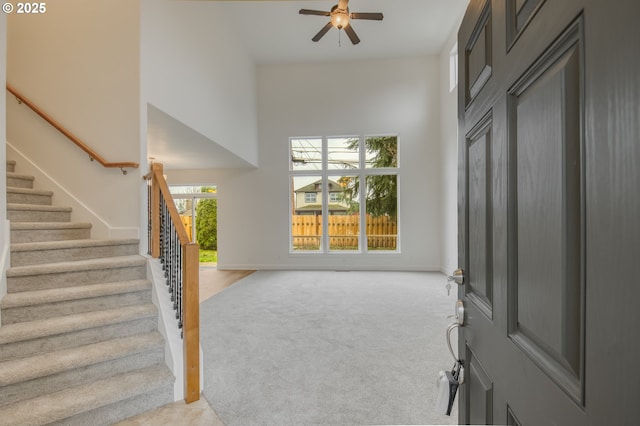 entrance foyer featuring stairway, light carpet, baseboards, and a towering ceiling