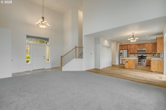 foyer entrance featuring stairs, a notable chandelier, light colored carpet, and baseboards