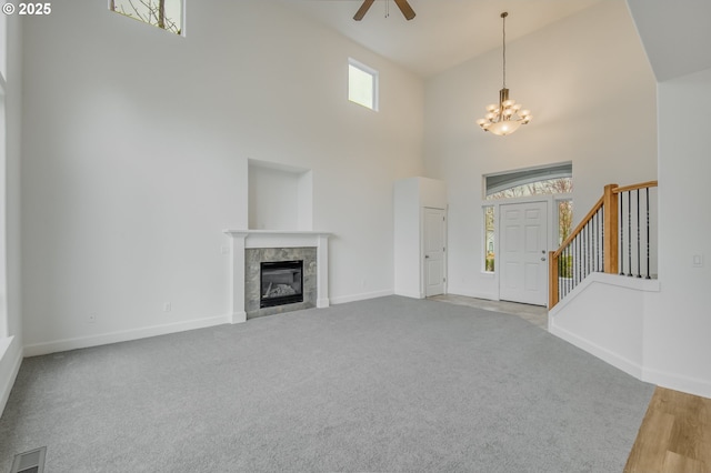 unfurnished living room featuring visible vents, baseboards, stairs, a tile fireplace, and a high ceiling