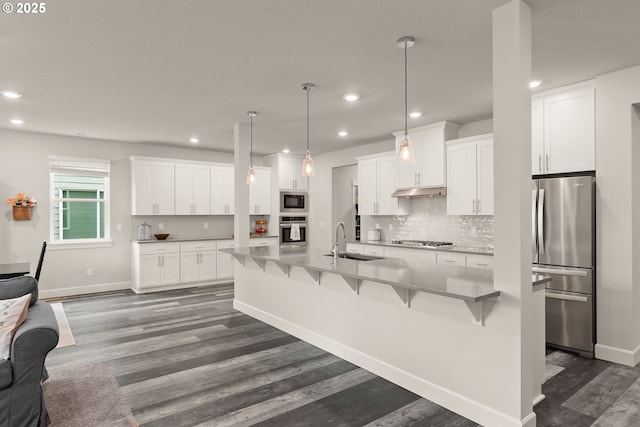 kitchen with appliances with stainless steel finishes, white cabinets, a sink, and dark wood-style floors