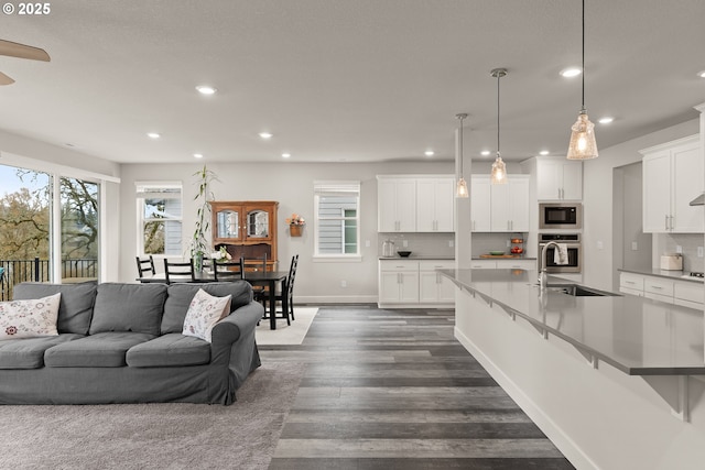 living area featuring dark wood-style floors, recessed lighting, a healthy amount of sunlight, and baseboards