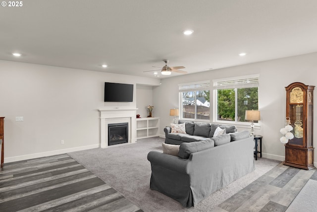 living area featuring baseboards, a glass covered fireplace, and recessed lighting