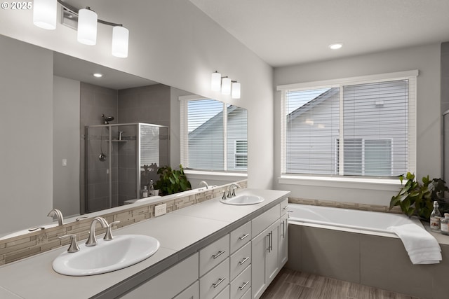 full bath with a sink, a shower stall, a bath, and double vanity