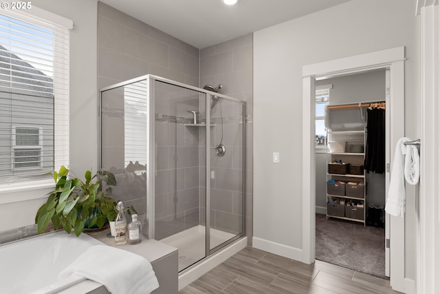 bathroom with a garden tub, a shower stall, baseboards, and a walk in closet