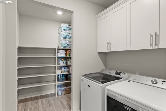 laundry room featuring cabinet space, separate washer and dryer, and wood finish floors