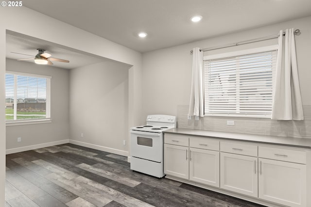 kitchen with white electric range oven, baseboards, white cabinets, and dark wood finished floors