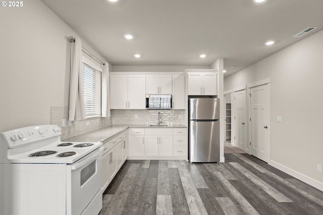 kitchen with electric range, visible vents, freestanding refrigerator, dark wood-style floors, and tasteful backsplash