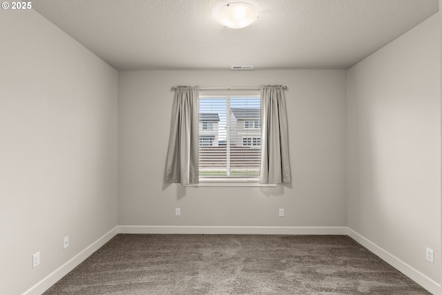 unfurnished room with a textured ceiling, dark colored carpet, visible vents, and baseboards