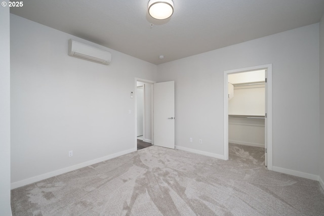 unfurnished bedroom featuring a closet, a walk in closet, light colored carpet, and an AC wall unit