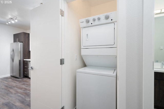 clothes washing area with stacked washer / drying machine and light hardwood / wood-style flooring