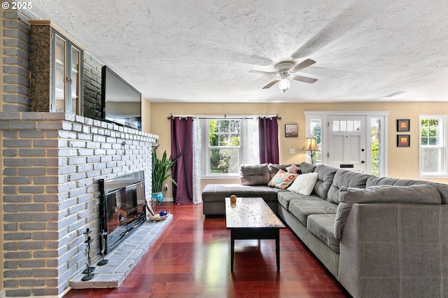 1112 S 6th St, Cottage Grove, OR 97424 - living room featuring dark wood-style flooring, healthy amount of natural light, ceiling fan, a brick fireplace, and a textured ceiling