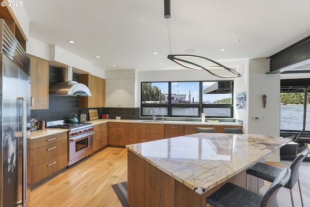 3939 N Marine Dr Unit 12, Portland, OR 97217 - kitchen featuring high quality appliances, wall chimney exhaust hood, modern cabinets, a sink, and light wood-style floors
