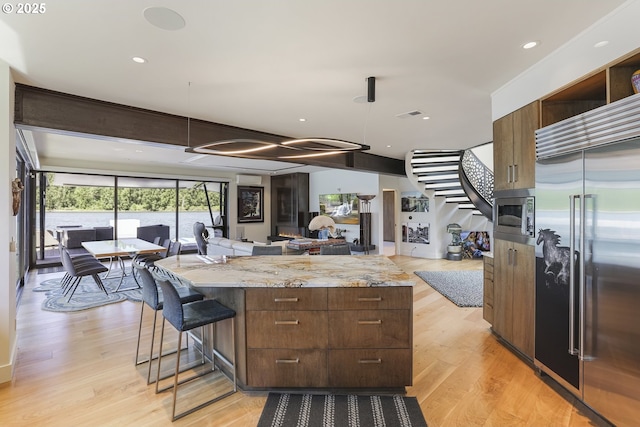 3939 N Marine Dr Unit 12, Portland, OR 97217 - kitchen featuring built in appliances, open floor plan, light wood finished floors, a center island, and modern cabinets