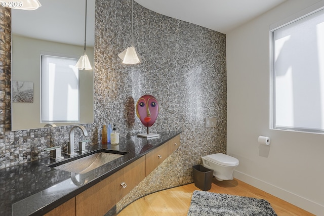 3939 N Marine Dr Unit 12, Portland, OR 97217 - bathroom with toilet, decorative backsplash, vanity, wood finished floors, and baseboards