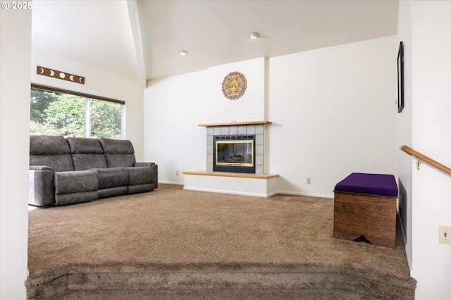 carpeted living area with a tiled fireplace, vaulted ceiling with beams, and baseboards